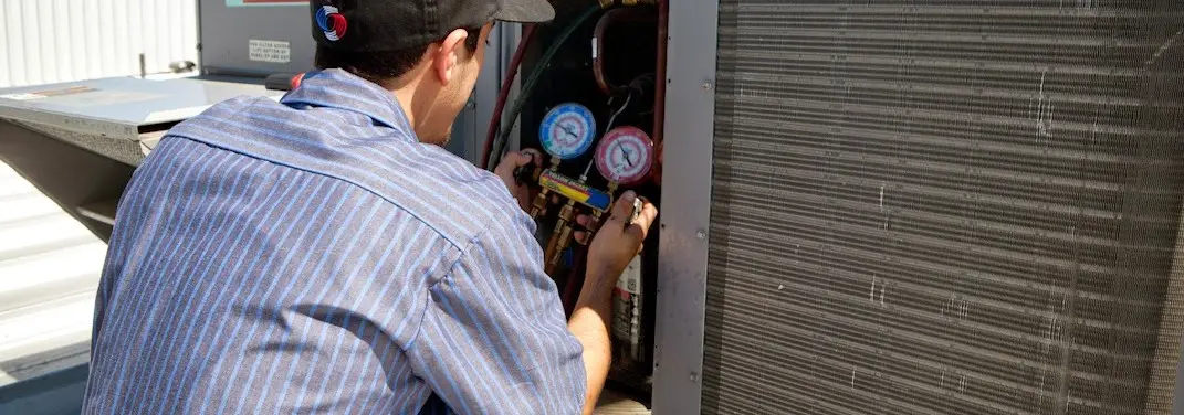 HVAC technician servicing a condenser unit in Mandan
