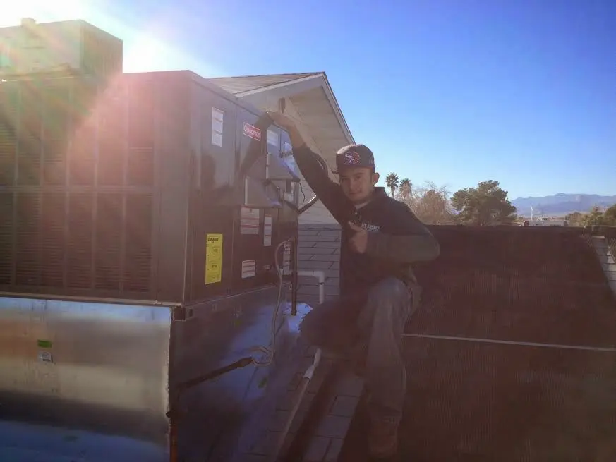 HVAC technician performing Air Duct Cleaning on a rooftop unit in Mandan